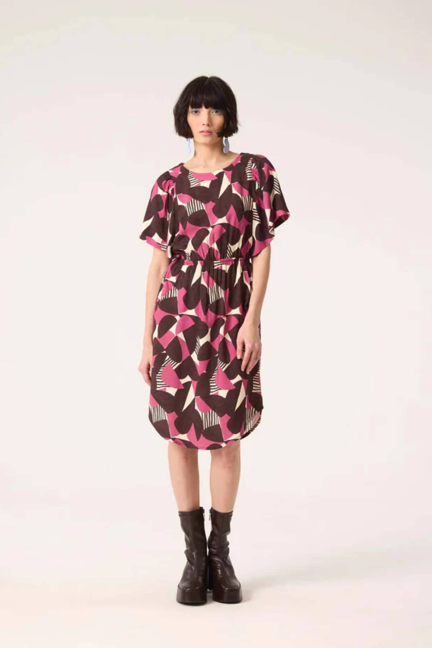 A woman wearing the Gemma Dress by Cokluch in Half Moon Berry print, standing in front of a white background
