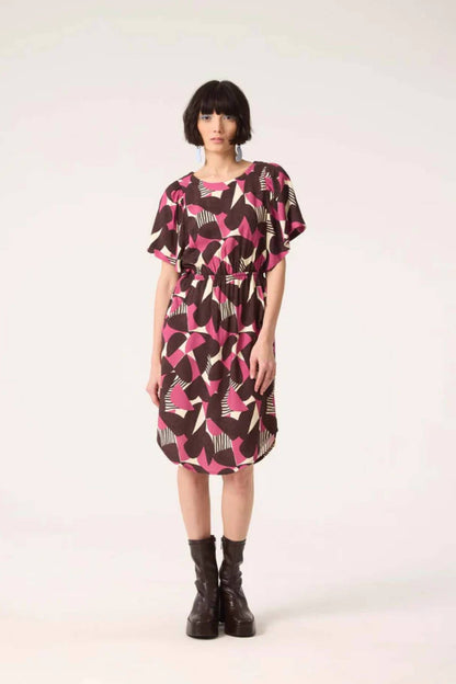 A woman wearing the Gemma Dress by Cokluch in Half Moon Berry print, standing in front of a white background
