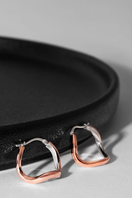 Copper silver lined hoop earrings on a black tray with a gray background