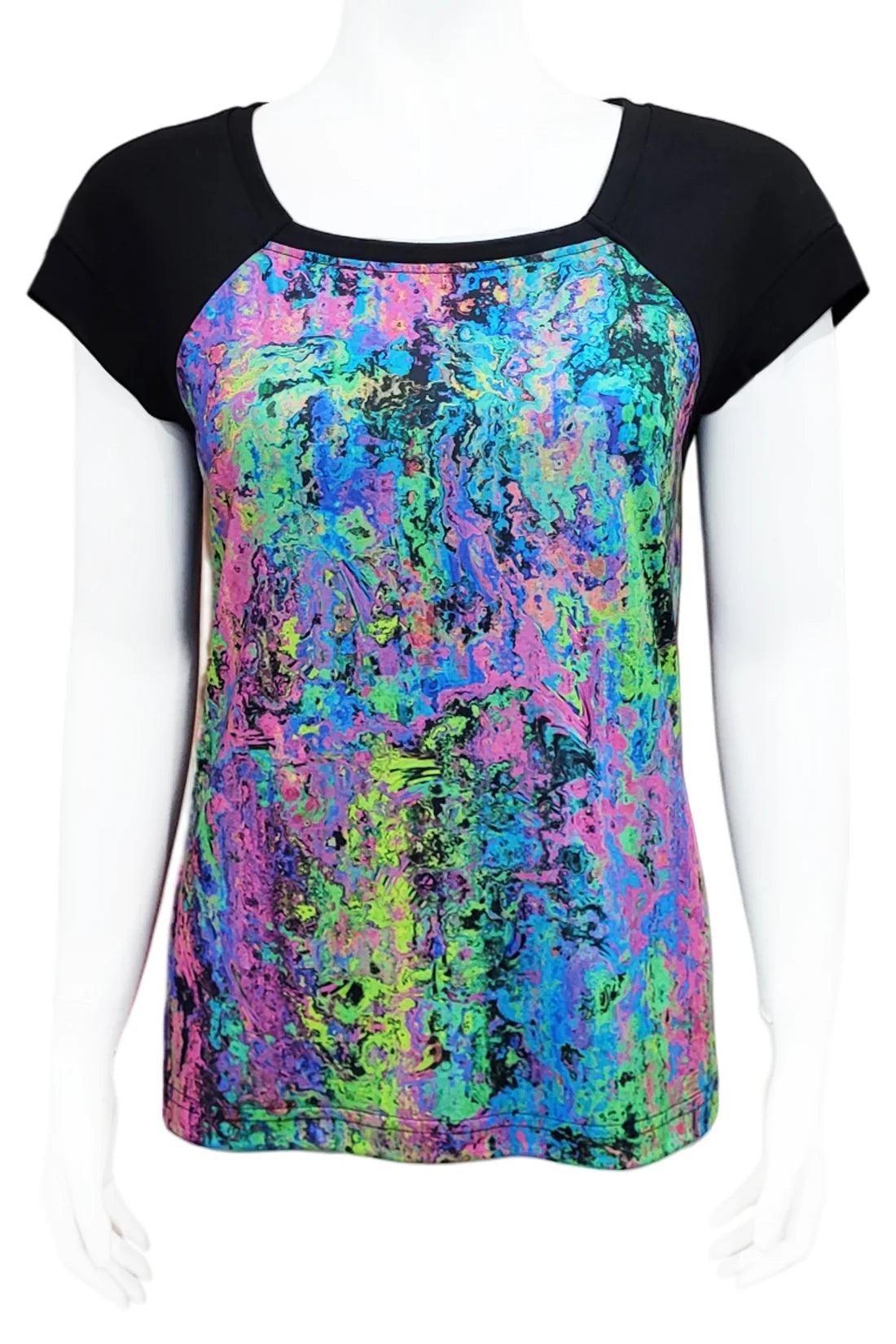 The Decades Era Tee by Mandala in 80s Neon, featuring an abstract print with contrasting black shoulders and back, is shown on a mannequin in front of a white background. 