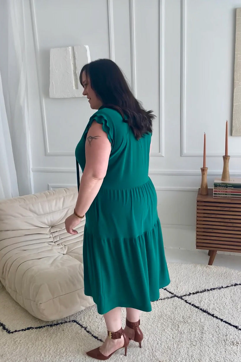 Back view of a woman wearing the Ruffle Sleeve Tie Dress by Dotty in emerald green