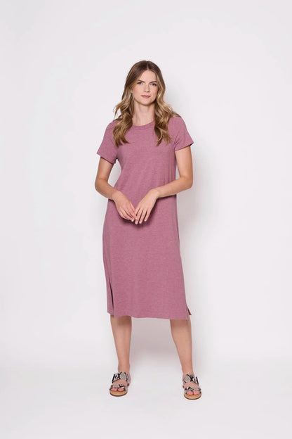 A woman wearing the Frances Midi  by Tangente in Heather Rose, short sleeved loose fitting dress with side slits. She is  standing against a plain background
