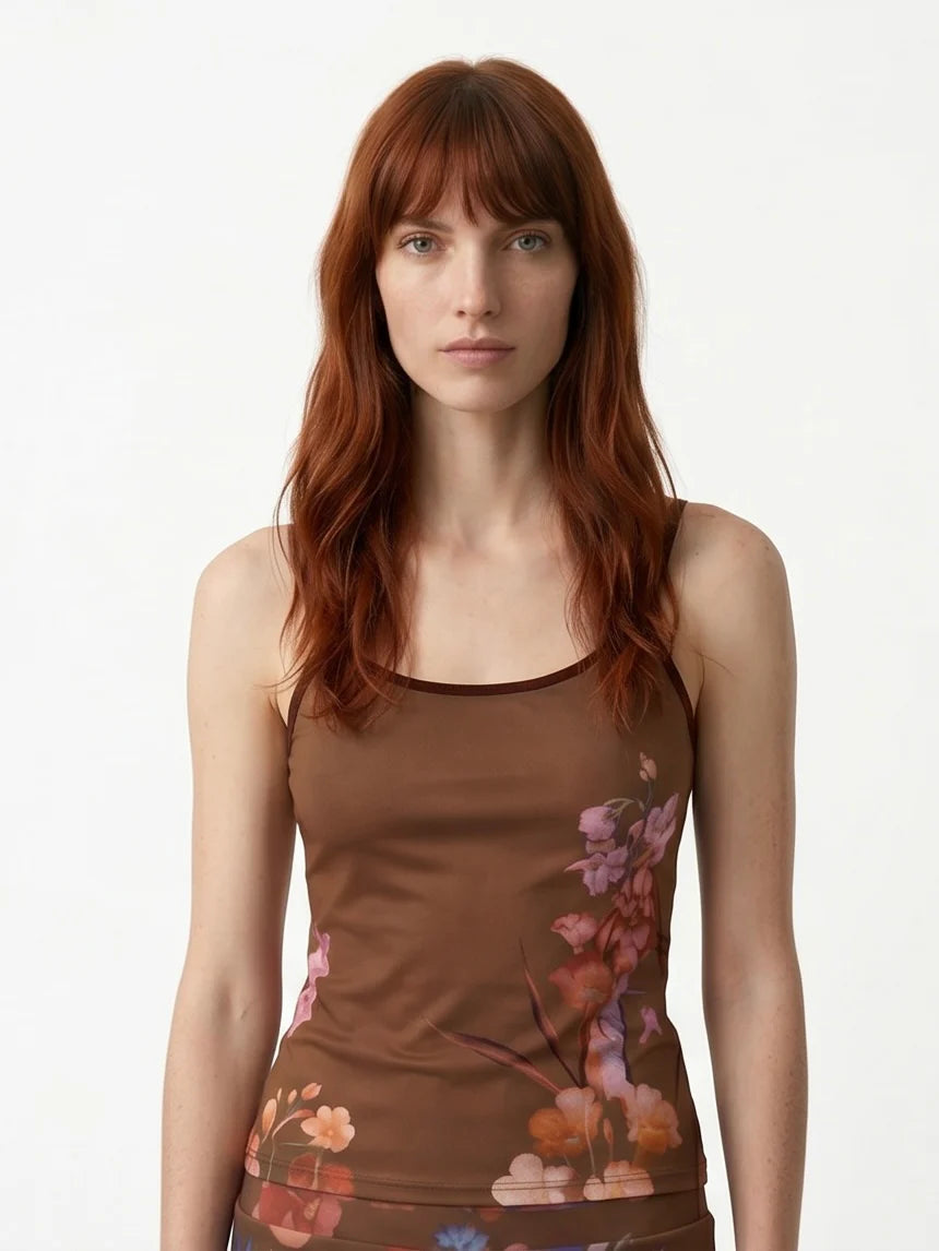 Waist up view of a woman wearing the Morganne Top by Kollontai, a brown floral tank top with spaghetti straps against a white background. 