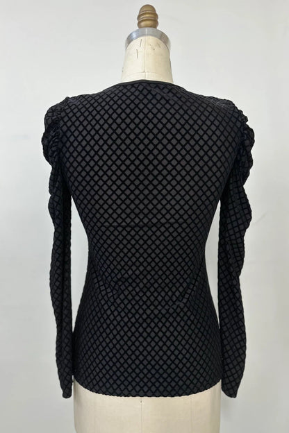 A back view of the Octavia Sweater by Kollontai, featuring black cut velvet in a diamond pattern, gathered shoulders, long sleeves, an oval neckline, and a slim fit, is shown on mannequin against a white background. 