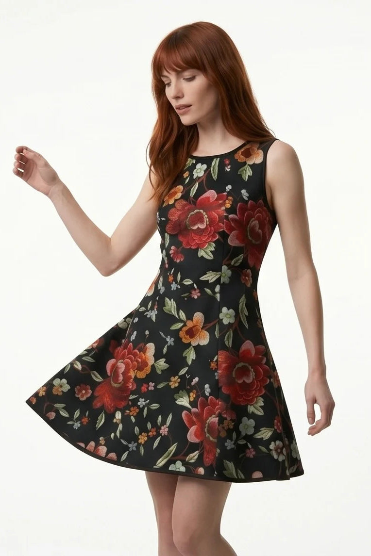 A woman wearing the Silba Dress FW26/27 by Kollontai in Black Floral, a short sleeveless dress with princess seams and an above the knee skirt. She is standing against a white background. 