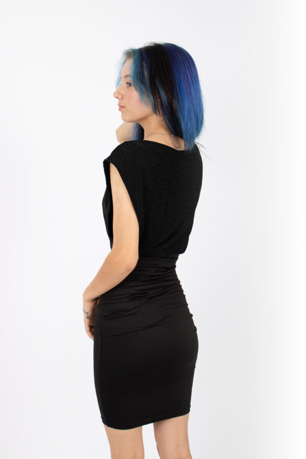 Back view of a woman wearing the Saki Top by Infime in glitter Black with a black skirt, standing in front of a white background 