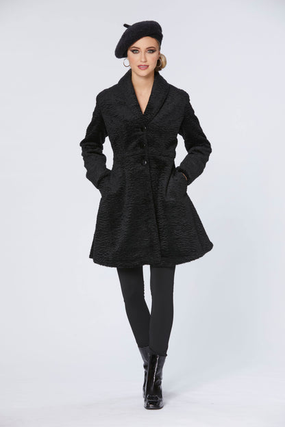 A woman wearing the Spies Jacket by Luc Fontaine in Black, a fit and flare above the knee coat in boucle fabric,  with black pants and a black beret, standing in front of a white background 