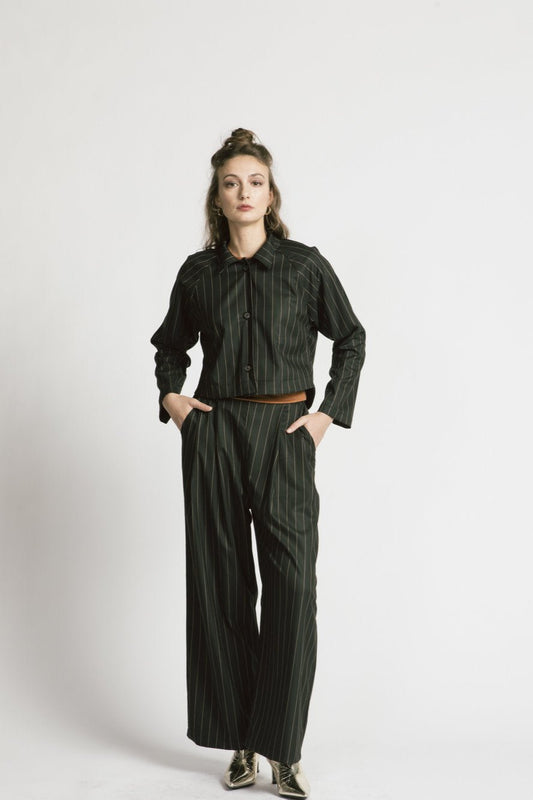 A woman wearing the Maurice Jacket by Allison Wonderland in pinstripe, with the Katherine Pant, standing in front of a white background 