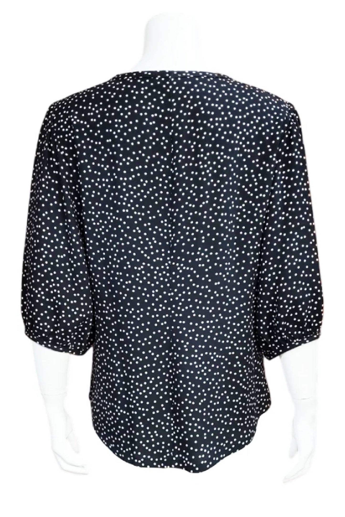 The back of the  Lydia Creeper Blouse by Mandala in Black/WhiteDot is shown in front of a white background. It features a jewel neck, puffed 3/4 sleeves, and a scooped hem. 