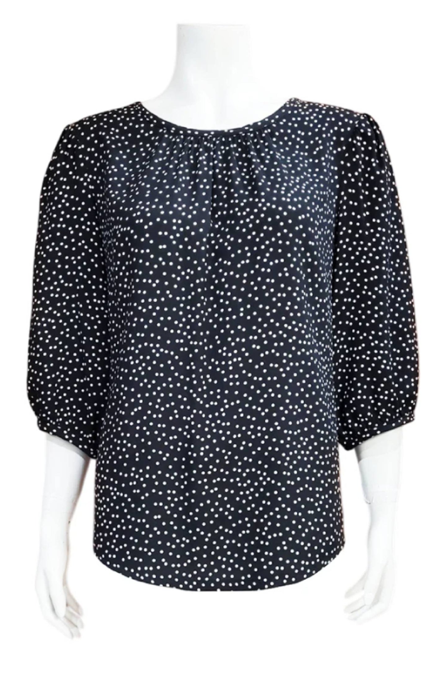 The Lydia Blouse by Mandala in Black/WhiteDot is shown in front of a white background. It features a jewel neck, puffed 3/4 sleeves, and a scooped hem. 