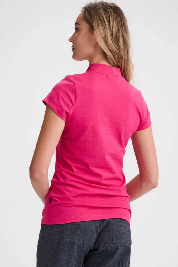 Back view of a woman wearing the Belleterre Top by Message Factory in Fuchsia, with a high neck, short sleeves, and a slim fit. She's wearing it with grey pants and standing in front of a white background 