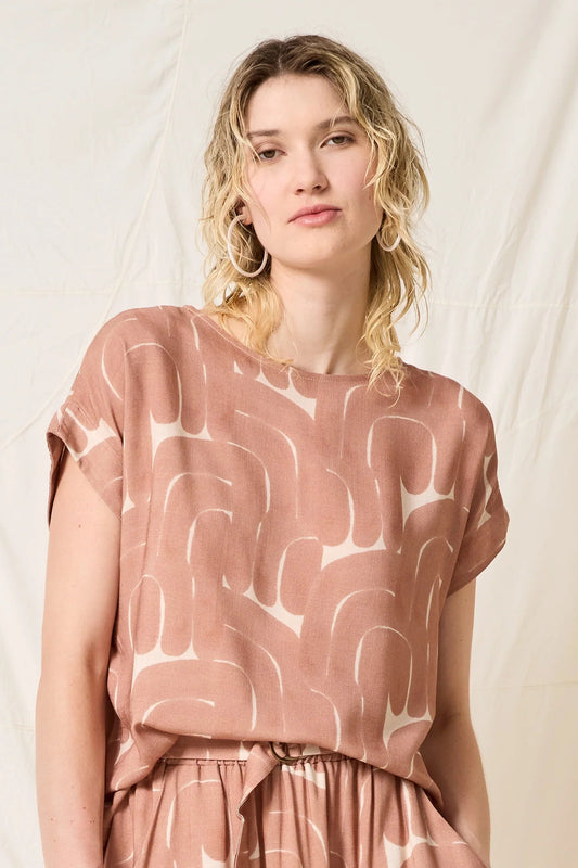 Woman wearing a pink dress with abstract white patterns against a plain background