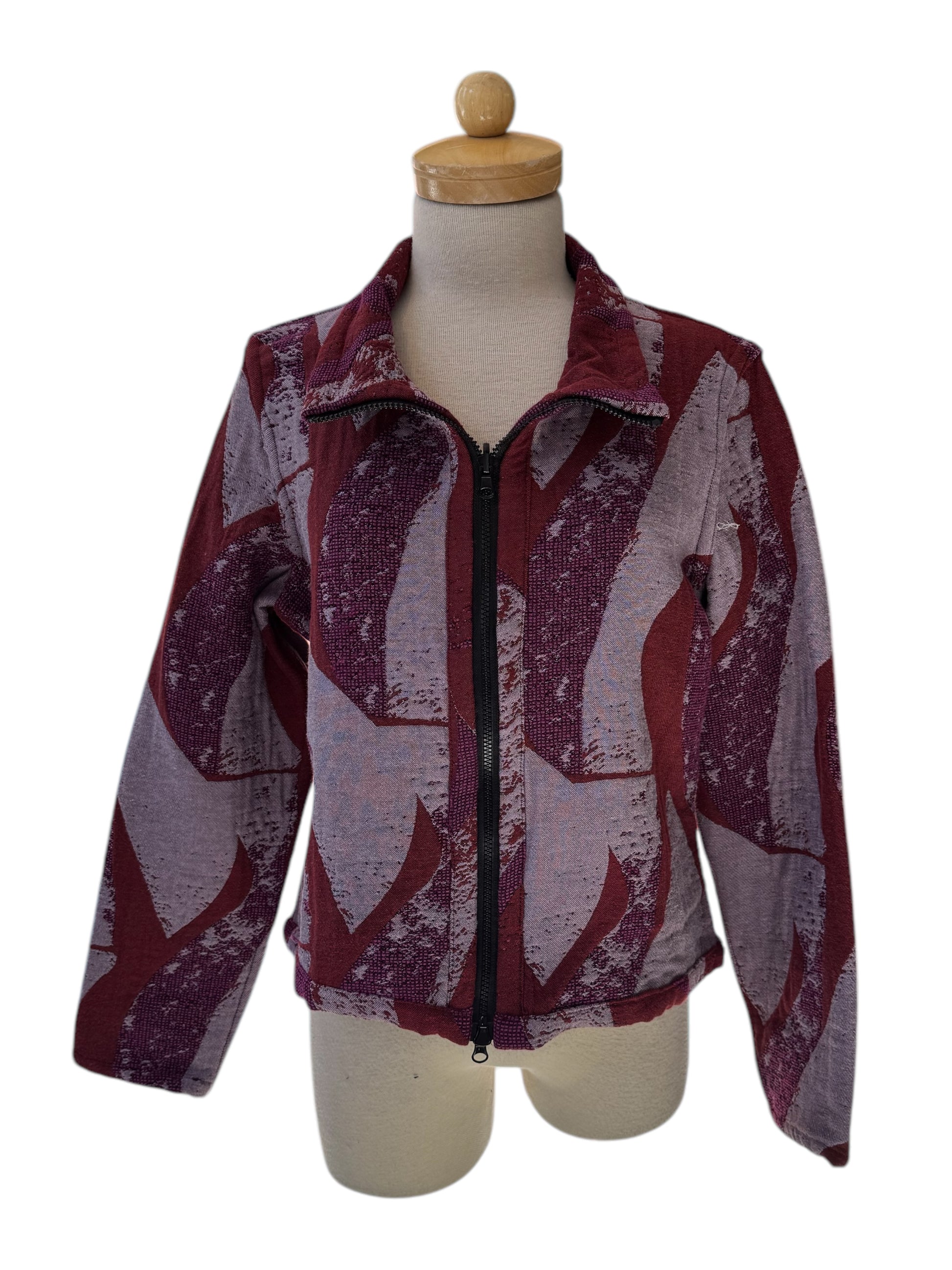 The Reversible Short Bomber Jacket by Véronique d’Aragon in purple, a cropped jacket with a classic collar and a zip front that's reversible inside out, is show on a mannequin against a white background. 