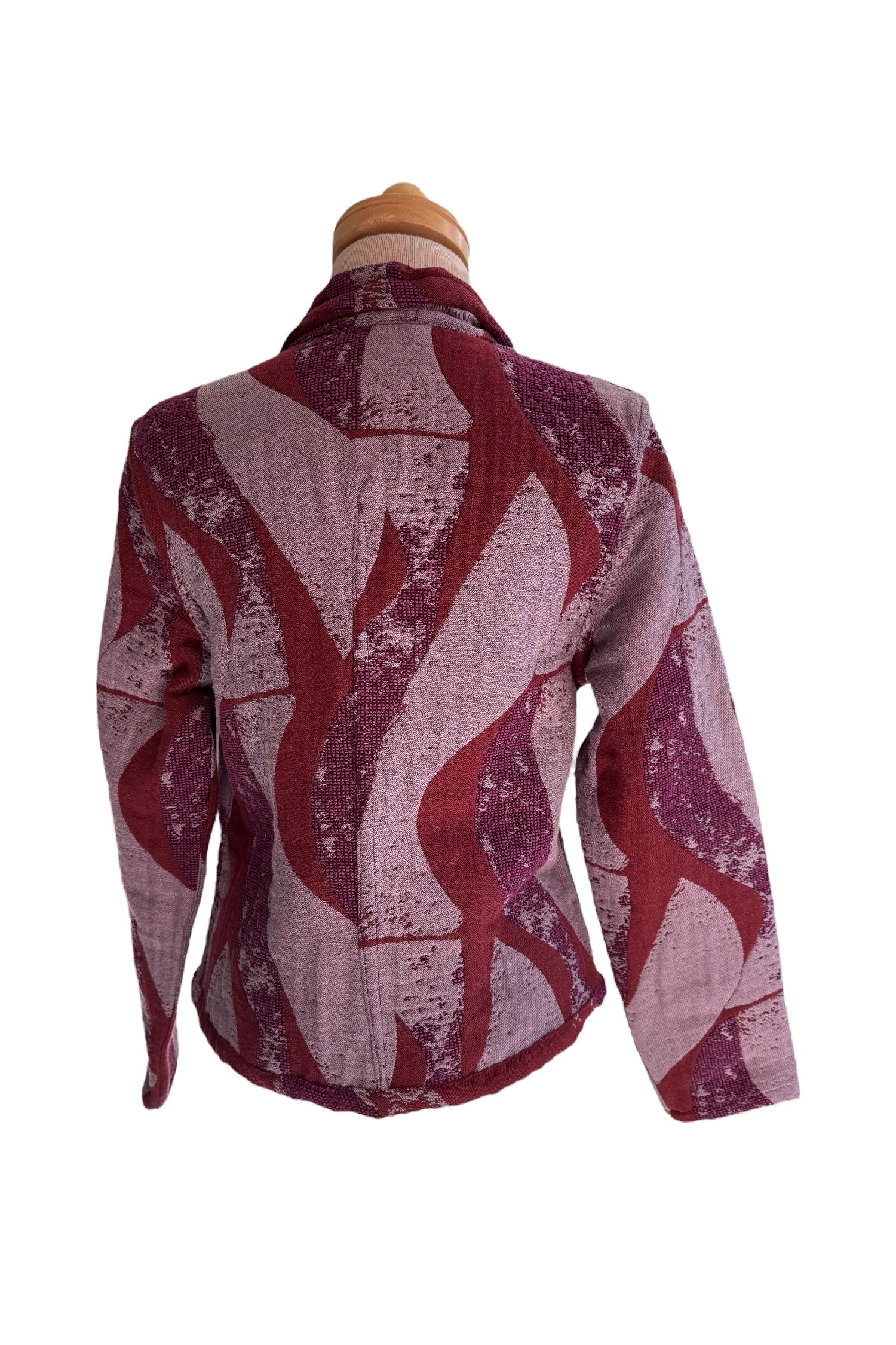 A back view of the Reversible Short Bomber Jacket by Véronique d’Aragon in purple, a cropped jacket with a classic collar and a zip front that's reversible inside out, is show on a mannequin against a white background. 