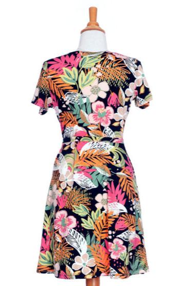 The back of the Macarena Dress by Rien ne se Perd in Tropical print, a short-sleeved faux-wrap dress with a drawstring waist and a flared above-the-knee skirt, is shown on a mannequin in front of a white background. 