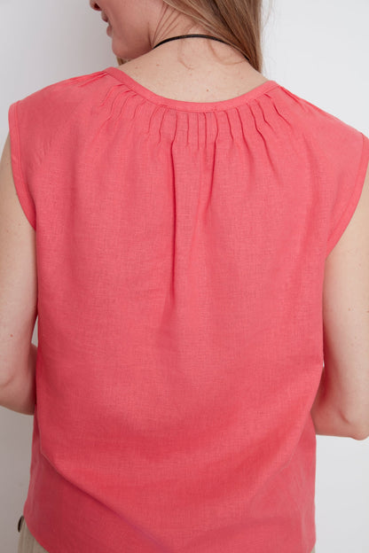 Back close up view of a woman wearing the Sabrina Top by Julei in coral, with raglan cap sleeves, a notched v-neck with pleat details, and a pleated back yoke. 