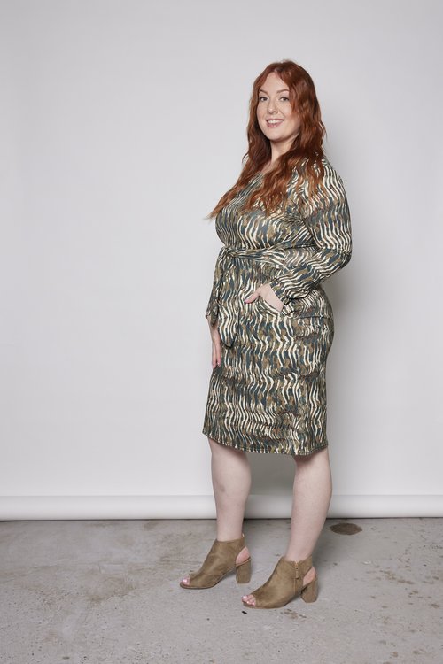 Side view of a woman wearing the Gwen Dress by Tangente in Green print, standing in front of a white background 