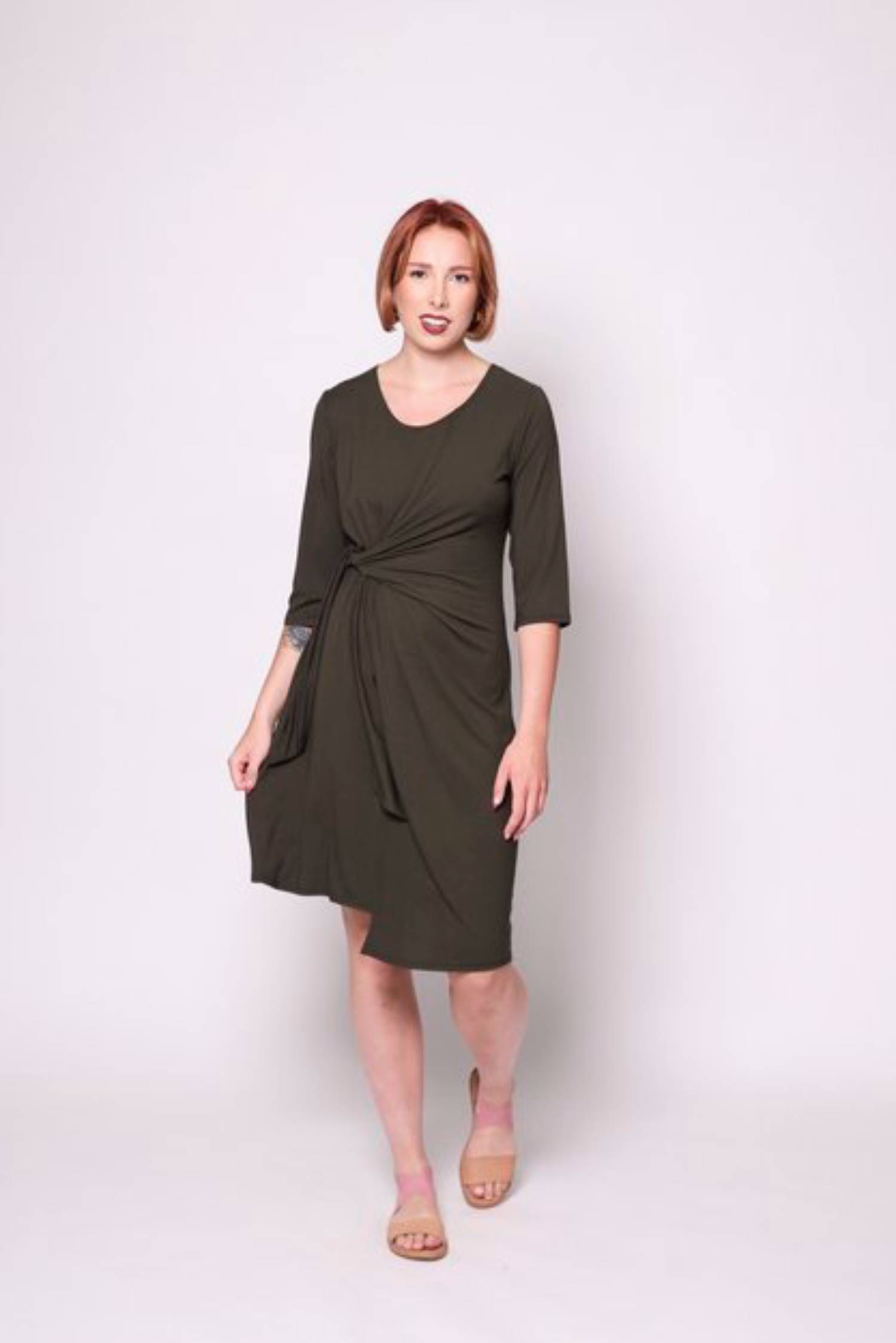 A woman wearing the Mariela Dress by Tangente in Spruce, standing in front of a white background 