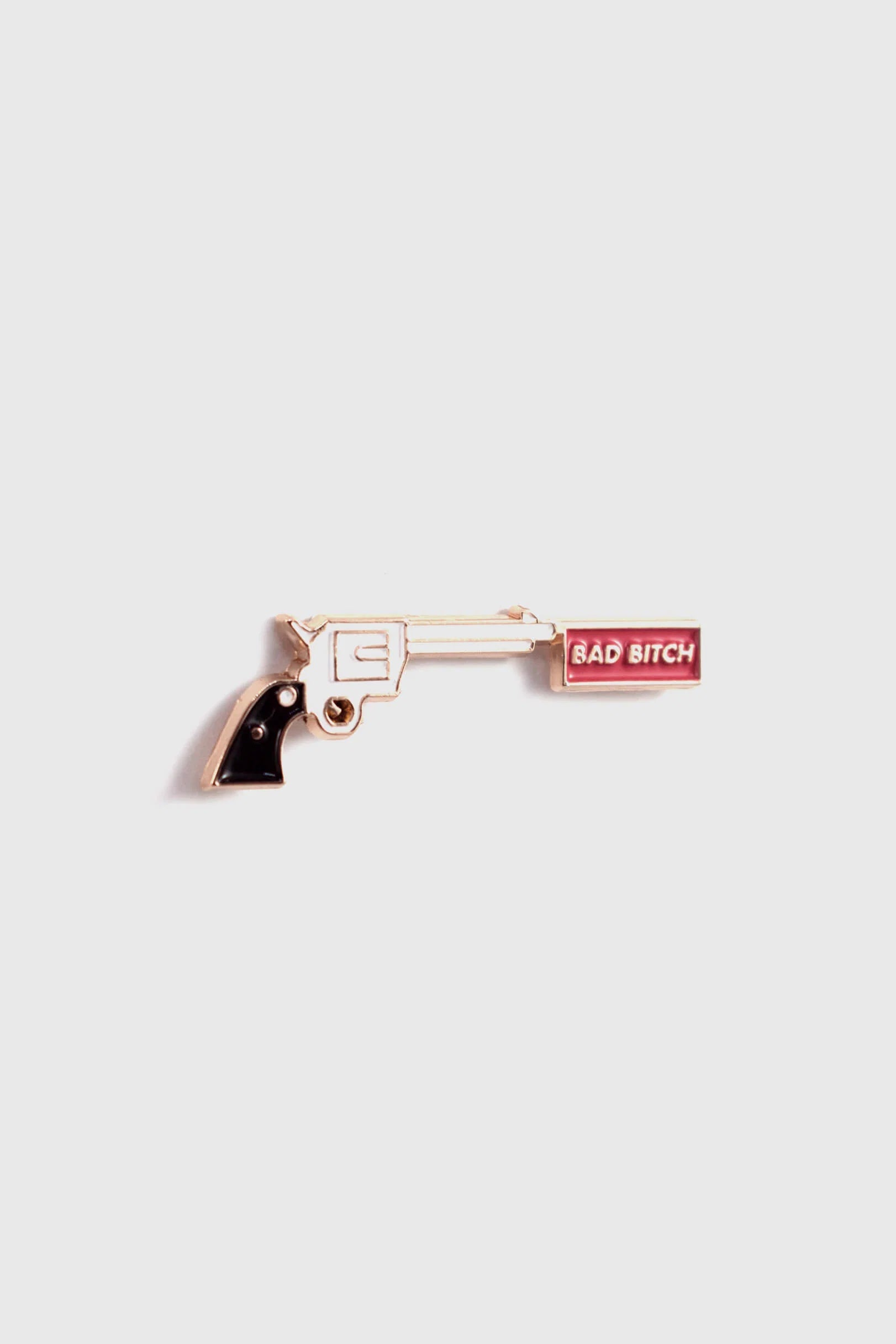The Bad Bitch Pin by Badaboöm Studio, featuring a gold gun with a red banner that reads "Bad Bitch", is shown against a white background. 