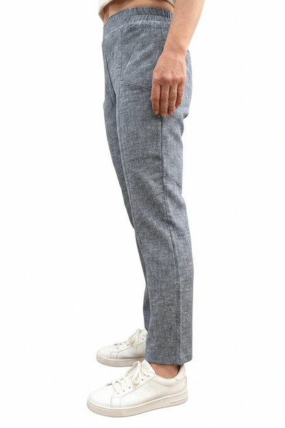 Side waist down view of a woman wearing the Cantley Short Pants by Message Factory in Natural Blue, slim cut capri pants with an elastic waist. She is standing in front of a plain background. 