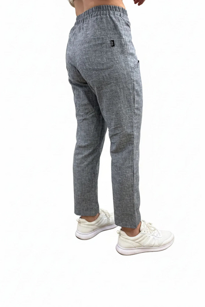 Back waist down view of a woman wearing the Cantley Short Pants by Message Factory in Natural Blue, slim cut capri pants with an elastic waist. She is standing in front of a plain background. 