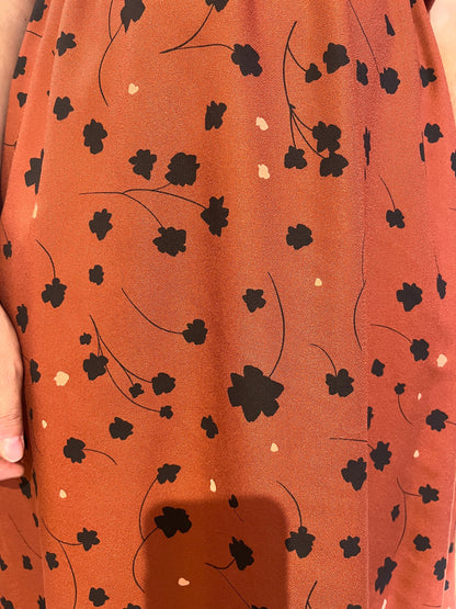 Close up detail of the Paloma Dress by Cherry Bobin in Black Floral with Bronze, with a classic collar, vintage brass buttons, short sleeves, an elastic waist, and a full below-the-knee skirt. 