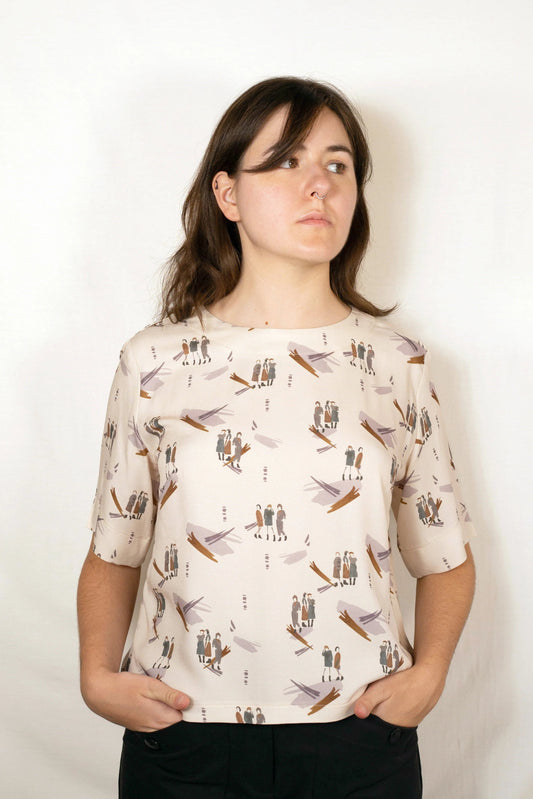 Person wearing a cream-colored t-shirt with printed design against a white background