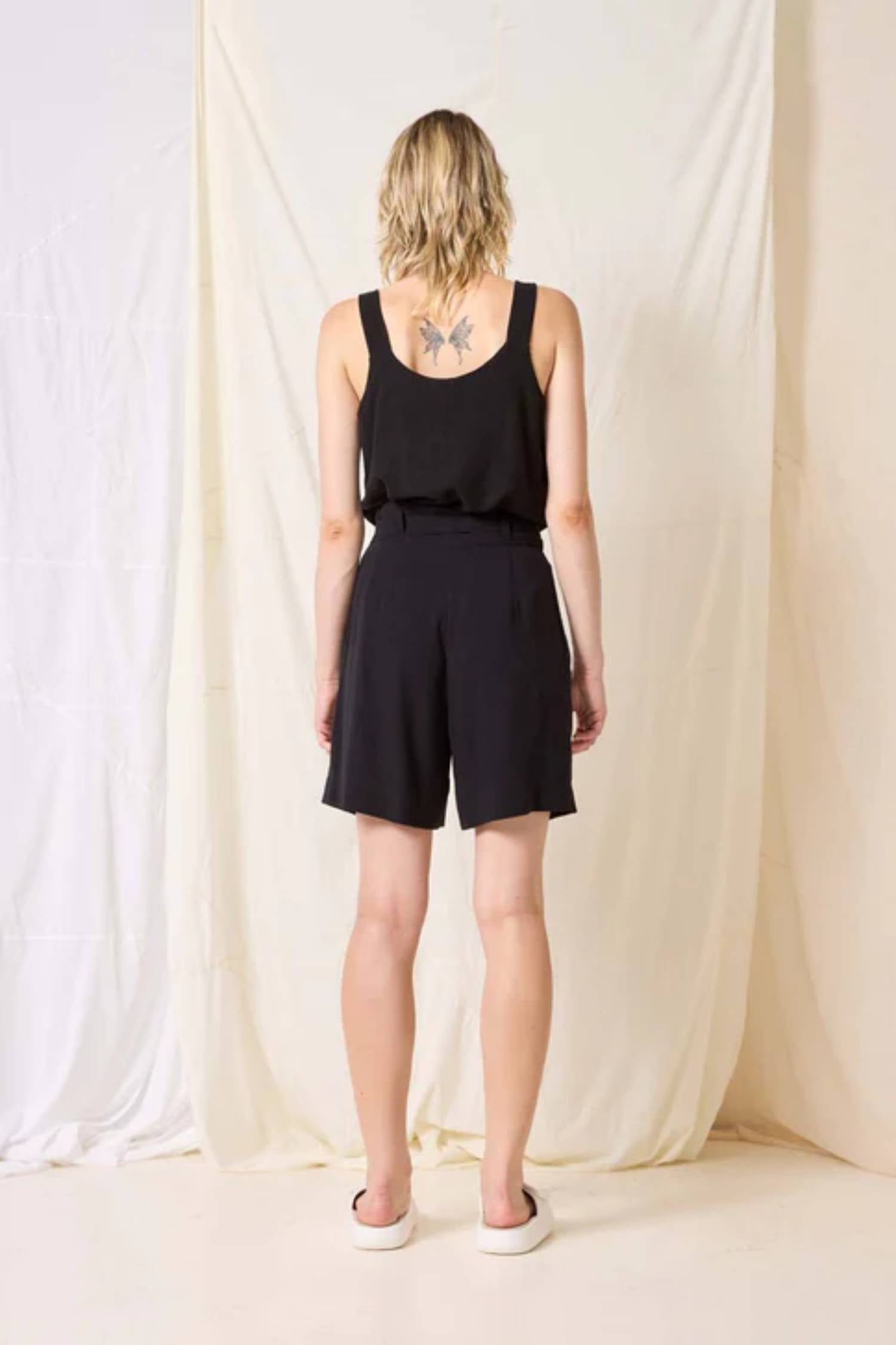 Kamala Short by Cokluch, Black, back view, high waist, paper-bag effect, ring belt, front pleats, button closure at waist, pockets, eco-fabric, OEKO-TEX certified, sizes XS to XL, made in Montreal