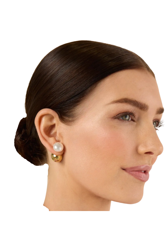 A close-up side profile of a woman with dark hair in a low bun, wearing 
the HoopLa Pearl and Gold Ball earring s