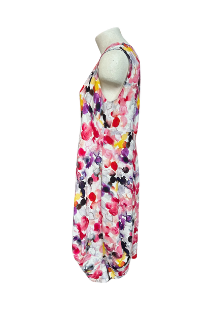 A side view of the Monica Dress by Solomia in Watercolour Print is shown on a mannequin against a white background. It's a sleeveless knee-length dress with a relaxed fit and uniquely angled bottom hem. 