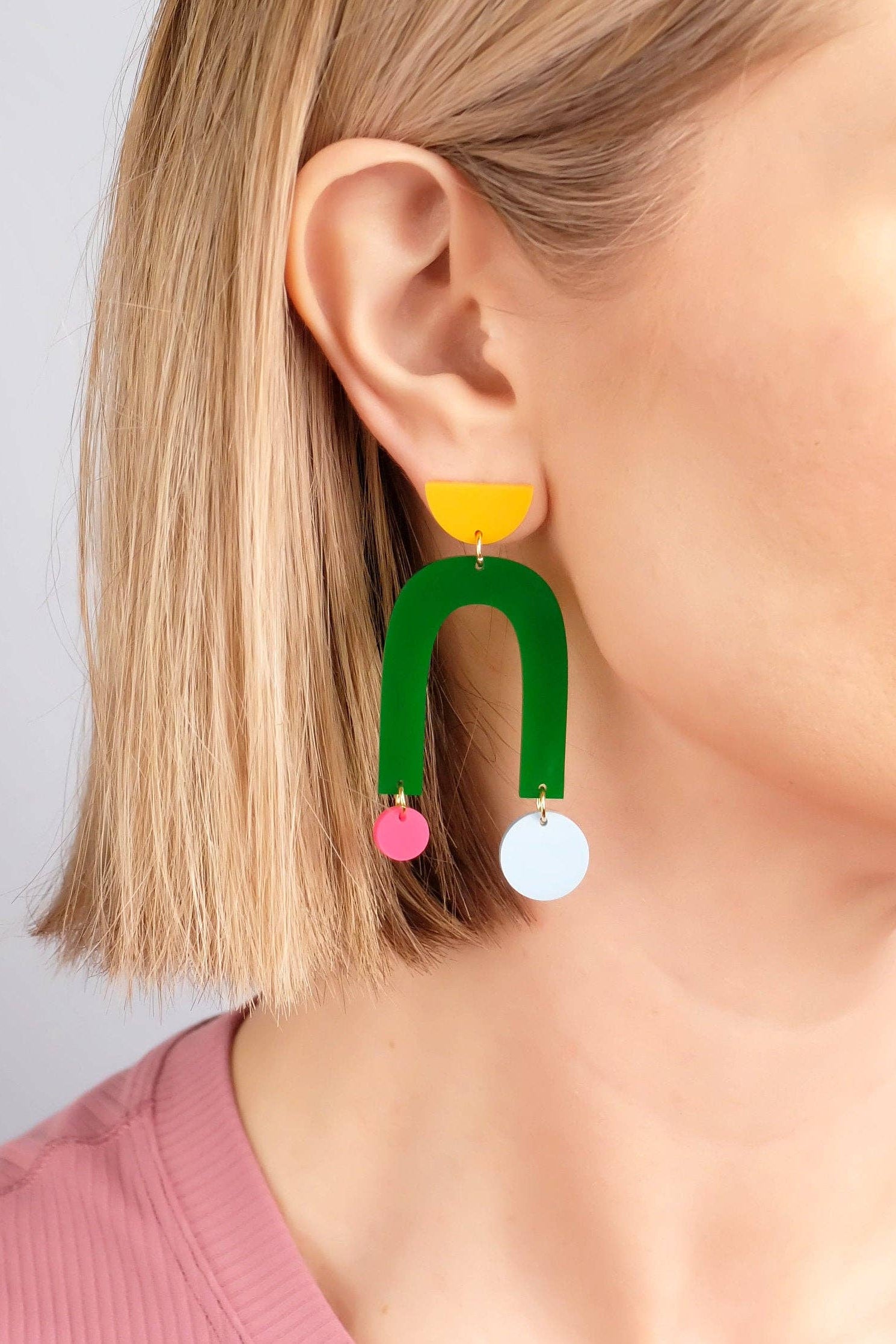 Colorful U-shaped earrings worn by a person with a plain background