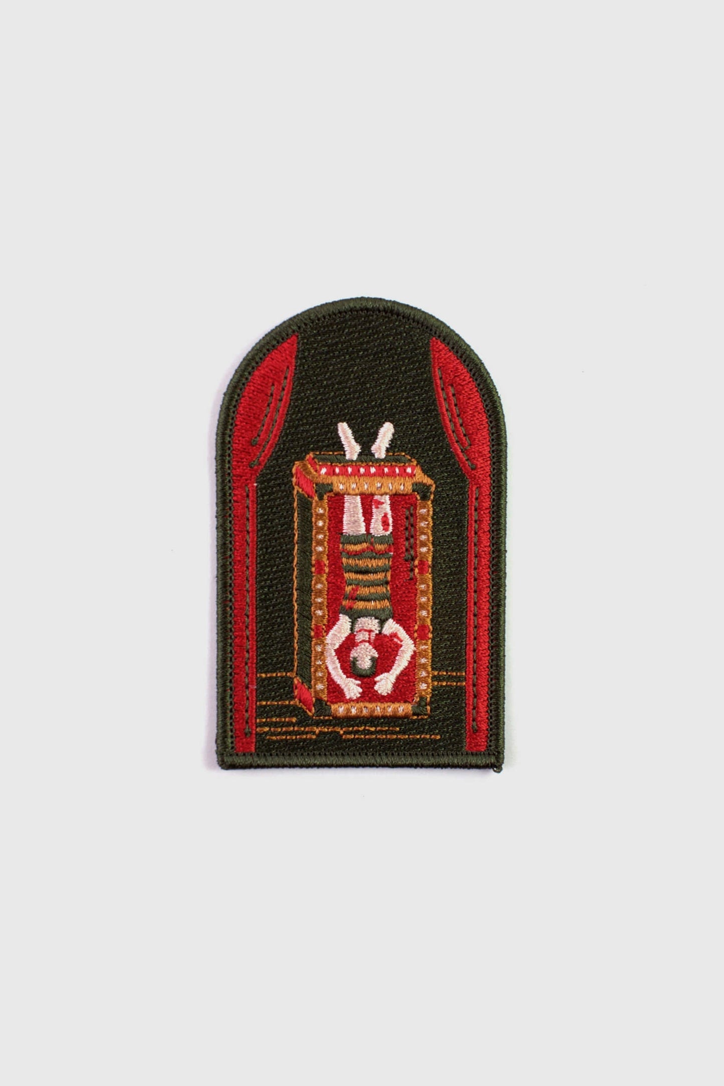 An embroidered arched patch from Badaboöm Studio showing Houdini upside down in a water tank. 
