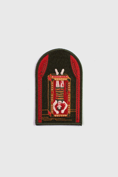 An embroidered arched patch from Badaboöm Studio showing Houdini upside down in a water tank. 
