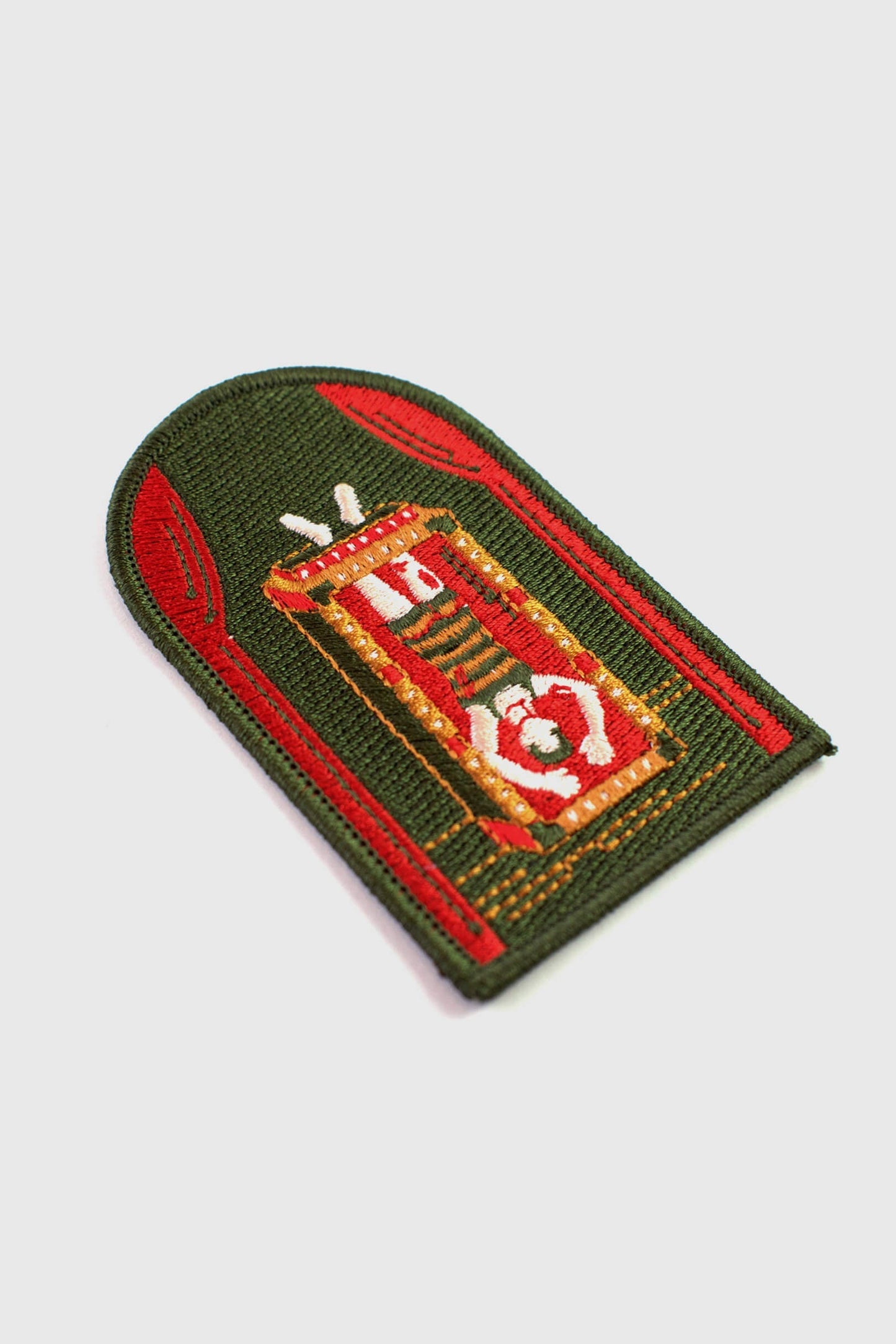 An embroidered arched patch from Badaboöm Studio showing Houdini upside down in a water tank. 