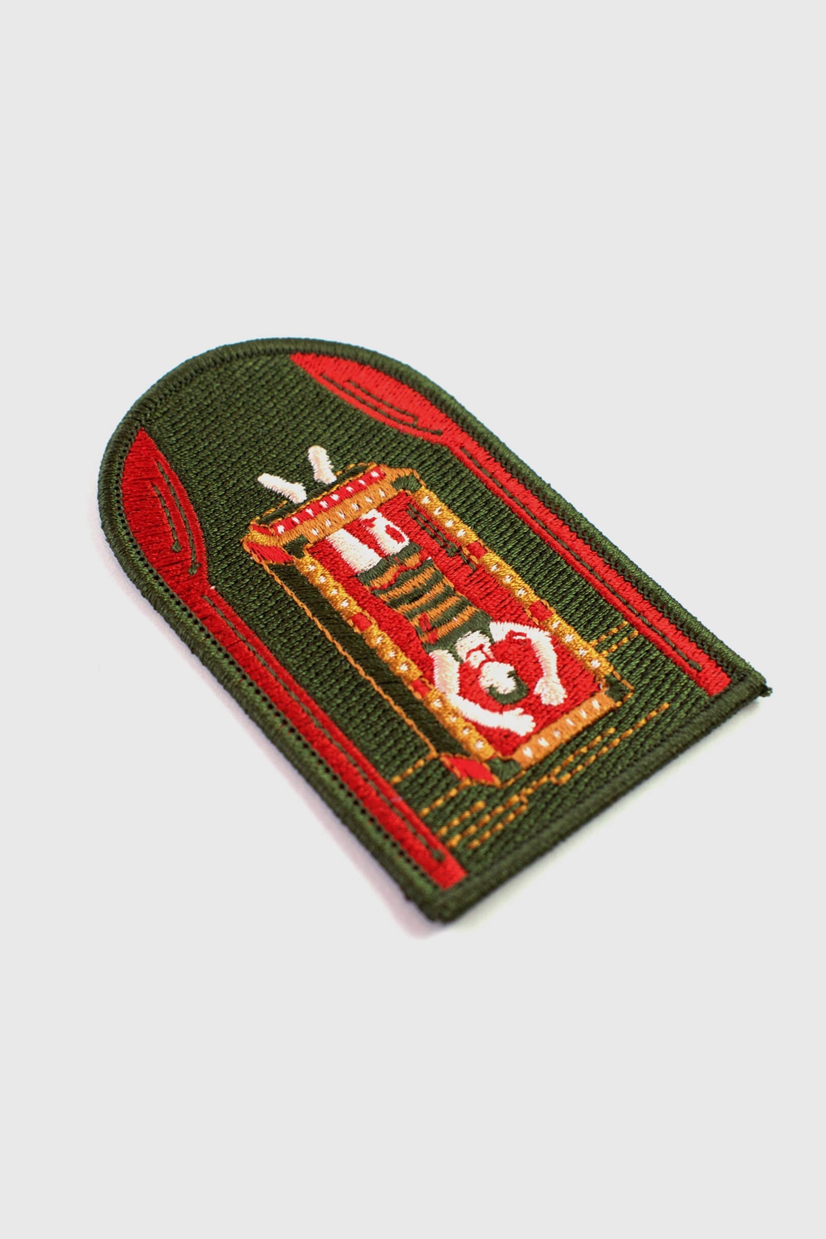 An embroidered arched patch from Badaboöm Studio showing Houdini upside down in a water tank. 