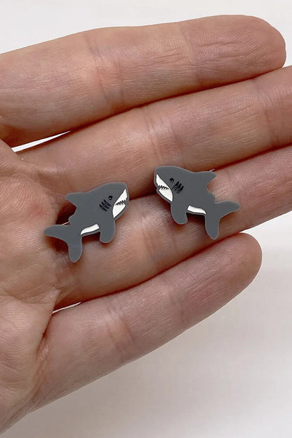 Hand holding Lilipop's shark-shaped earring against a plain background