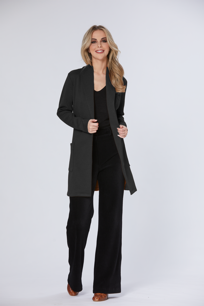 A woman wearing the Dop Cardigan by Luc Fontaine in Black with Black pants, standing in front of a white background 