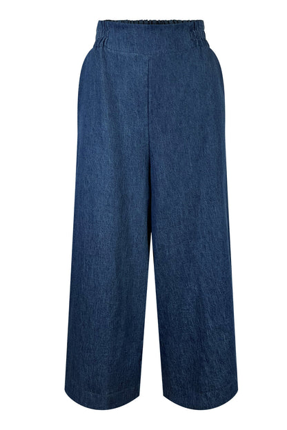 The Mateo Pants by Melow in Denim, ¾ wide leg pants with pull-on waistband that’s elasticized at the back, are shown against a white background. 