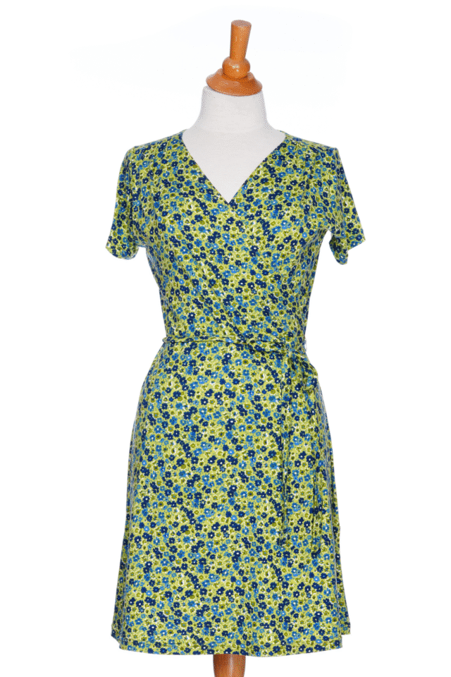 The Margarita Dress by Rien ne se Perd in Blue/Green floral print, with a faux wrap neckline, short sleeves, and short a-line skirt, is shown on a mannequin in front of a white background.