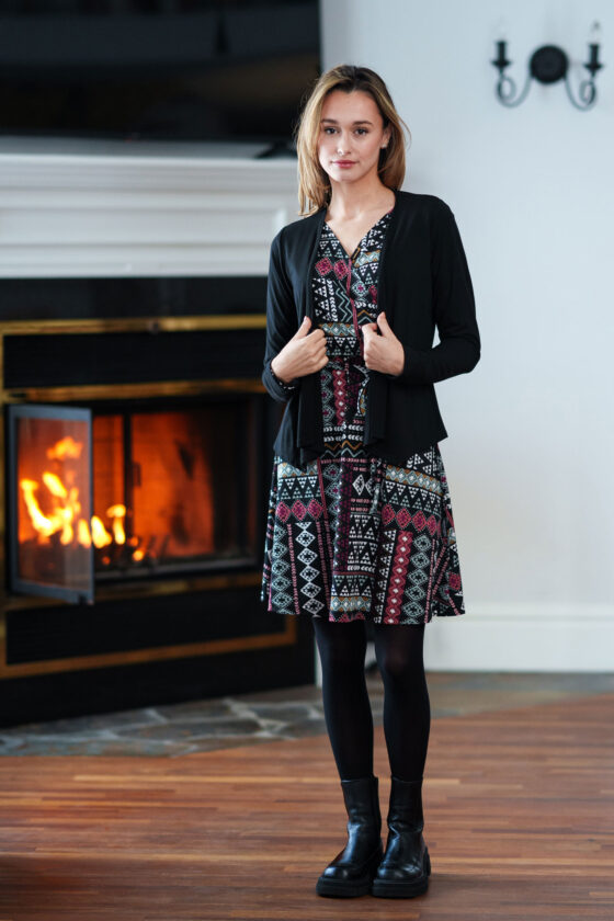 A woman wearing the Renoir Dress by Rien ne se Perd in Aztec, standing in front of a fireplace