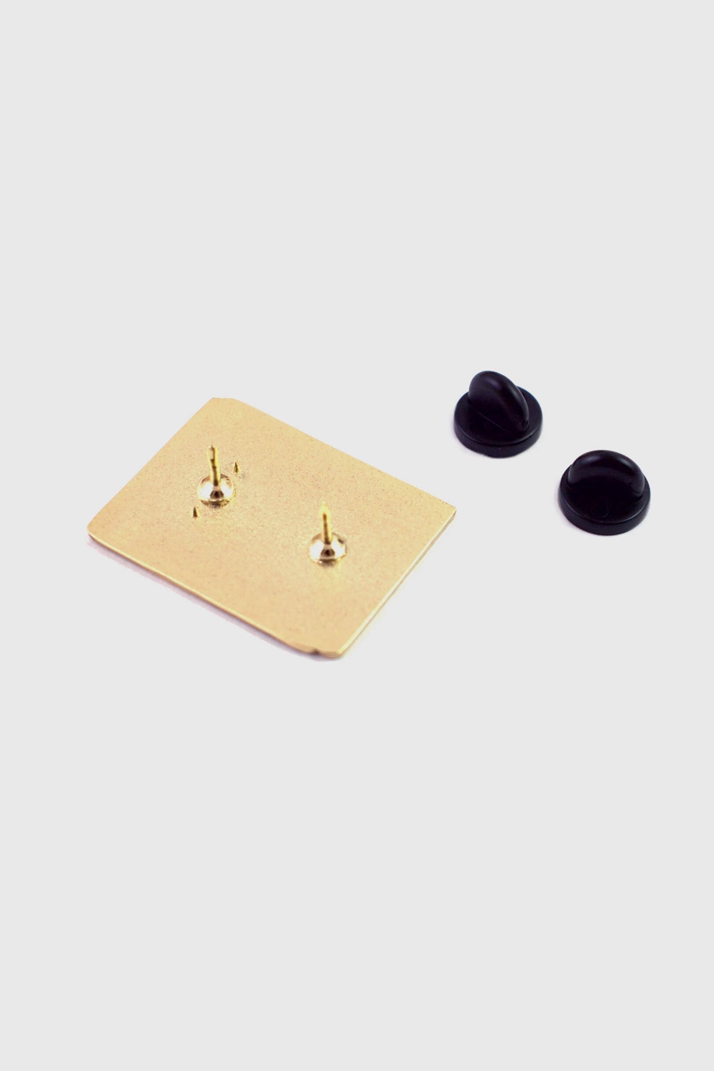 A back view of The World Domination Pin from Badaboöm Studio, a tiny book titled "Secret Plans for World Domination," is shown against a white background. 