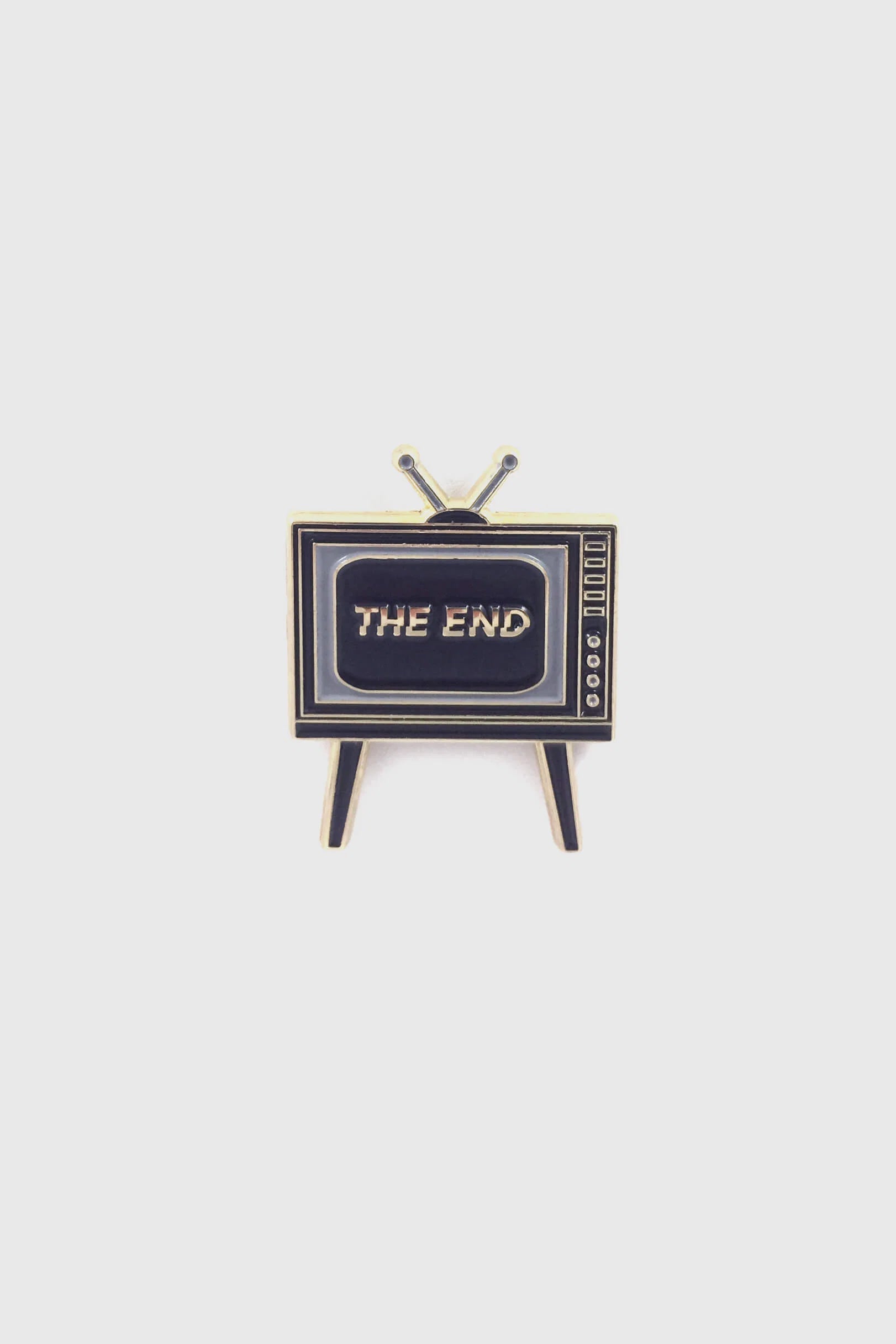 Badaboöm Studio's retro television-shaped enamel pin with 'THE END' lettering on the screen, set against a plain light grey background.