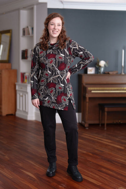 A woman wearing the Corno Tunic by Rien ne se Perd in Black and Red with a black skirt stands in front of a piano. 