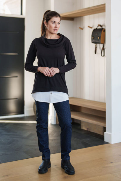 A woman wearing the Granite Pants by Rien ne se Perd in Denim Blue, standing in the entry way of a home