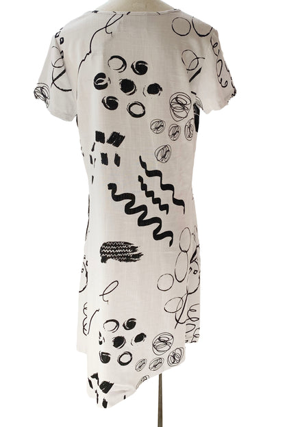 Mika Dress by Compli K, White with black abstract designs, back view, round neck, short sleeves, diagonal seams, asymmetrical hem, one pouch pocket, eco-fabric, rayon and linen, sizes XS to XXL, made in Montreal