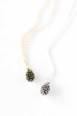 Tiny pine cone necklace by Birch Jewellery in silver and gold, flat lay