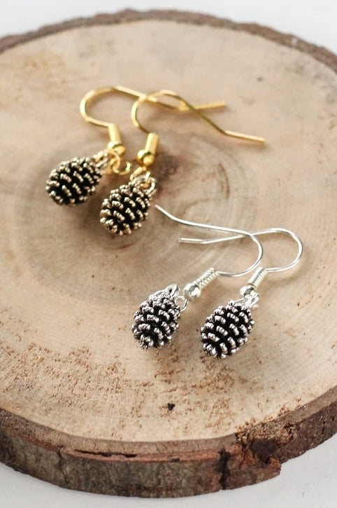 Pine cone earrings by Birch Jewellery; silver and gold, styled on a stump of wood