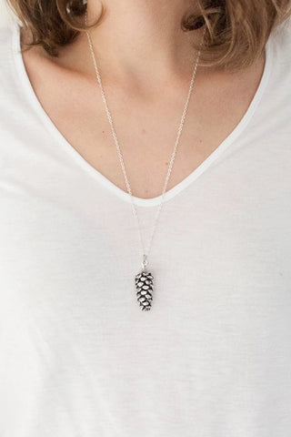 Large pine cone necklace by Birch Jewellery; worn on the neckline to show length; silver version styled with a basic white t-shirt