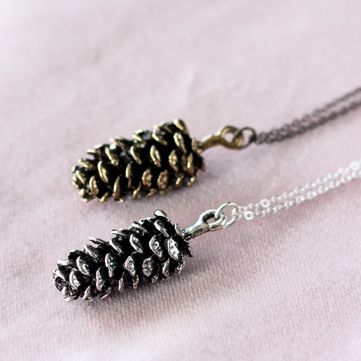 Large pine cone necklace by Birch Jewellery; flat lay; in silver and gold