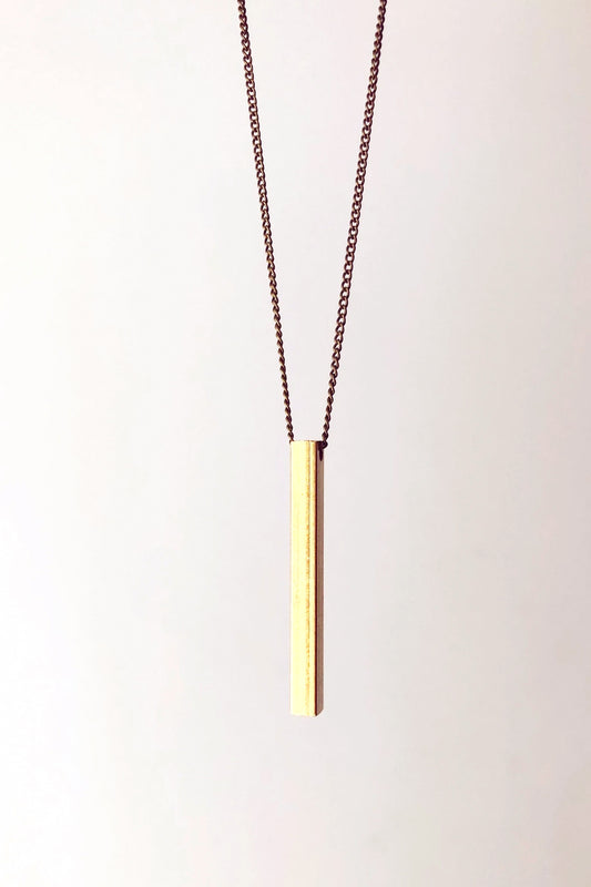 Beatrice necklace by Darlings of Denmark; mid-length chain; raw brass; vertical solid bar detail; close-up; flat lay